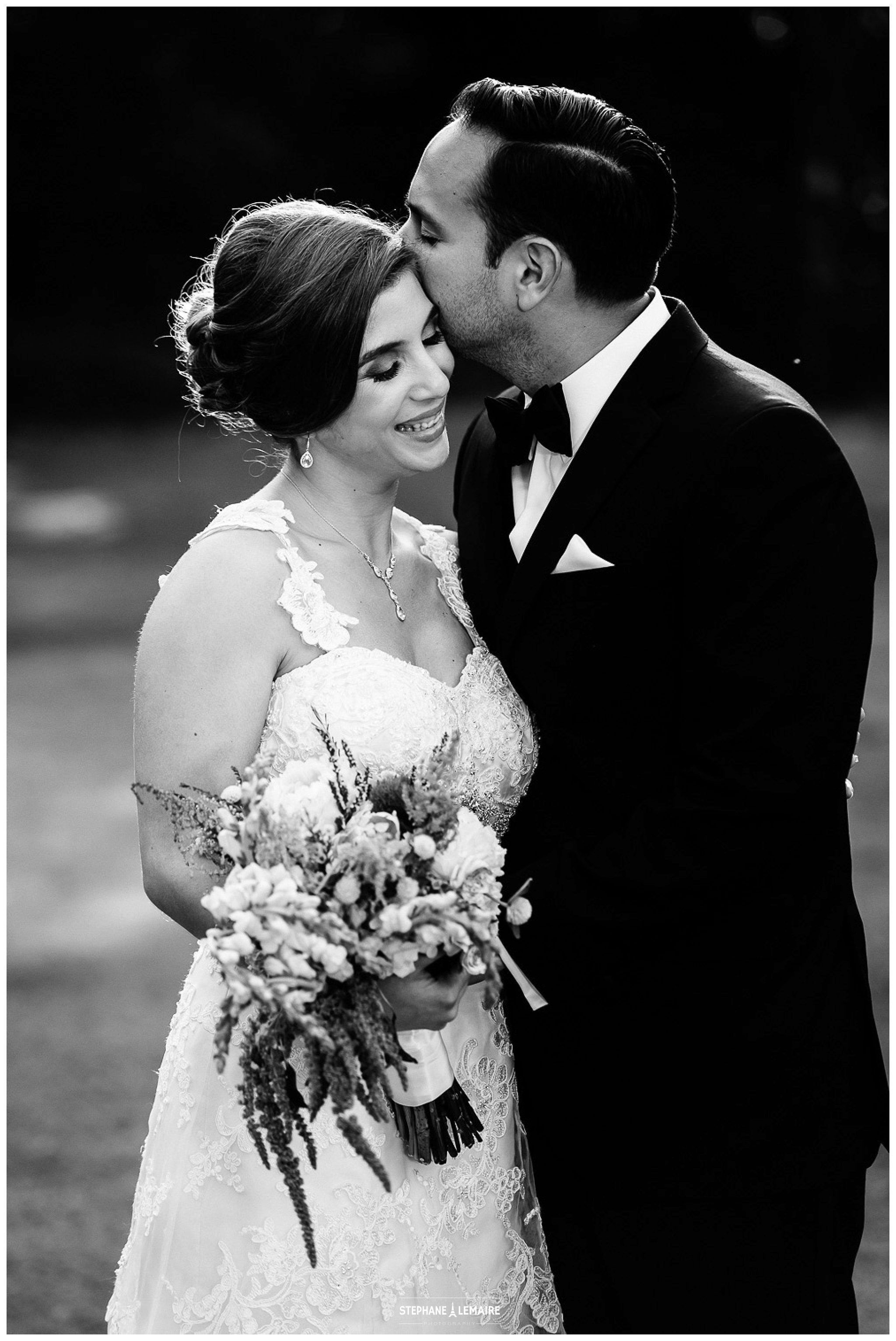 Black and white portrait of Groom kissing Bride's cheek