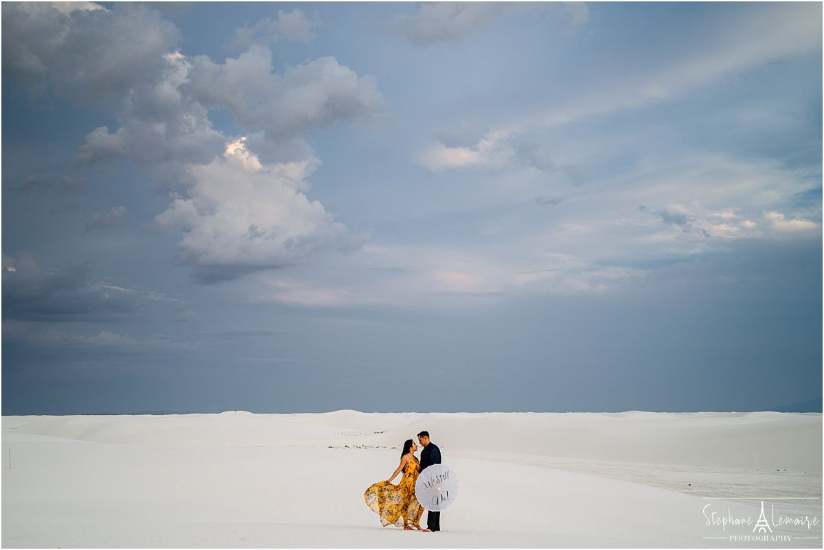 Couple holding an umbrella at White Sands National Monument by stephane Lemaire photography