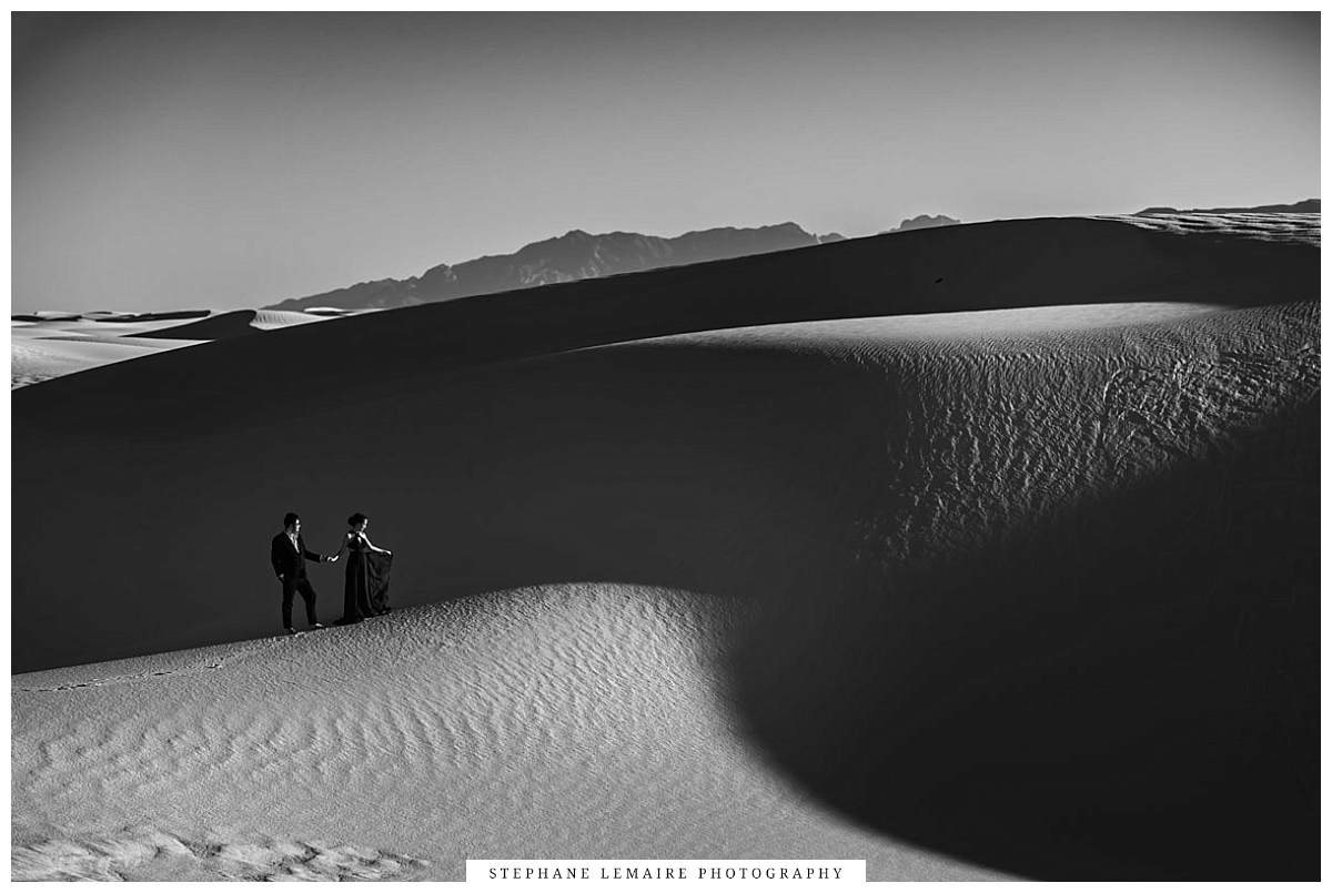 Black and white photo with a couple kissing on a dune at White Sands National Park.