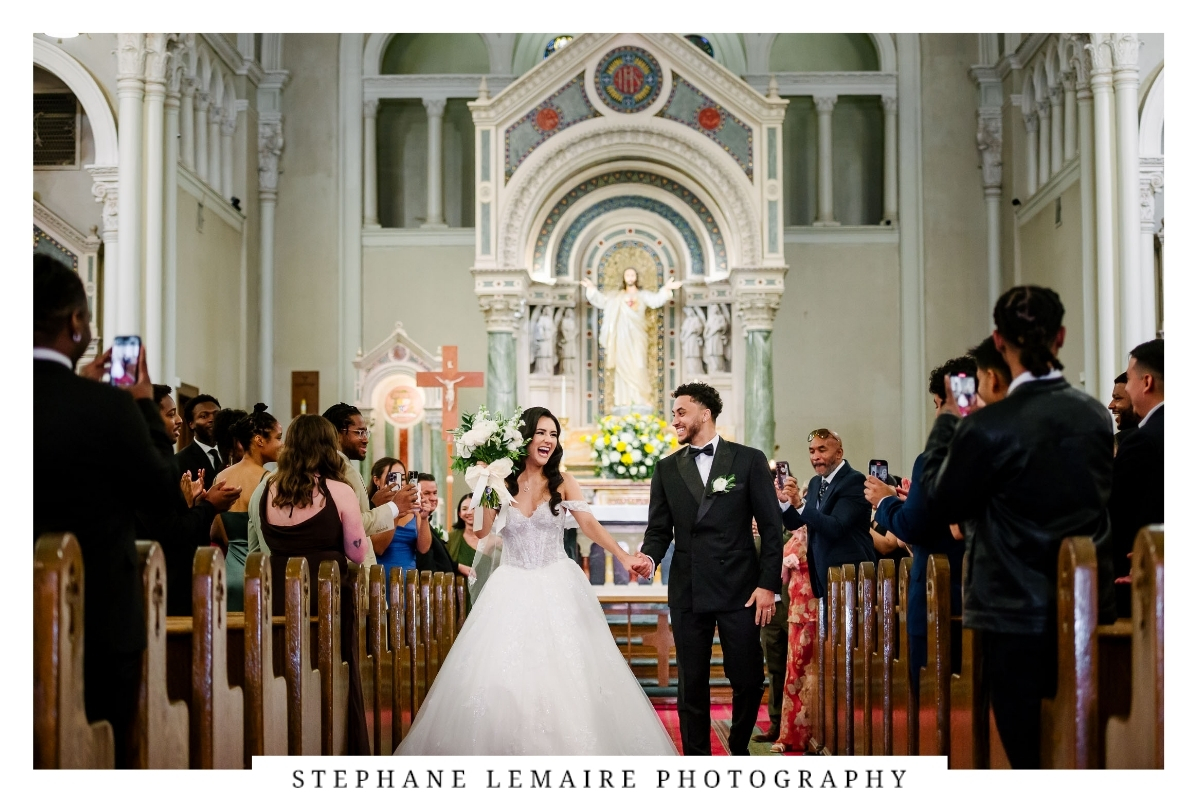 Newlyweds smiling as they walk down the aisle together after their St. Patrick Cathedral wedding ceremony.