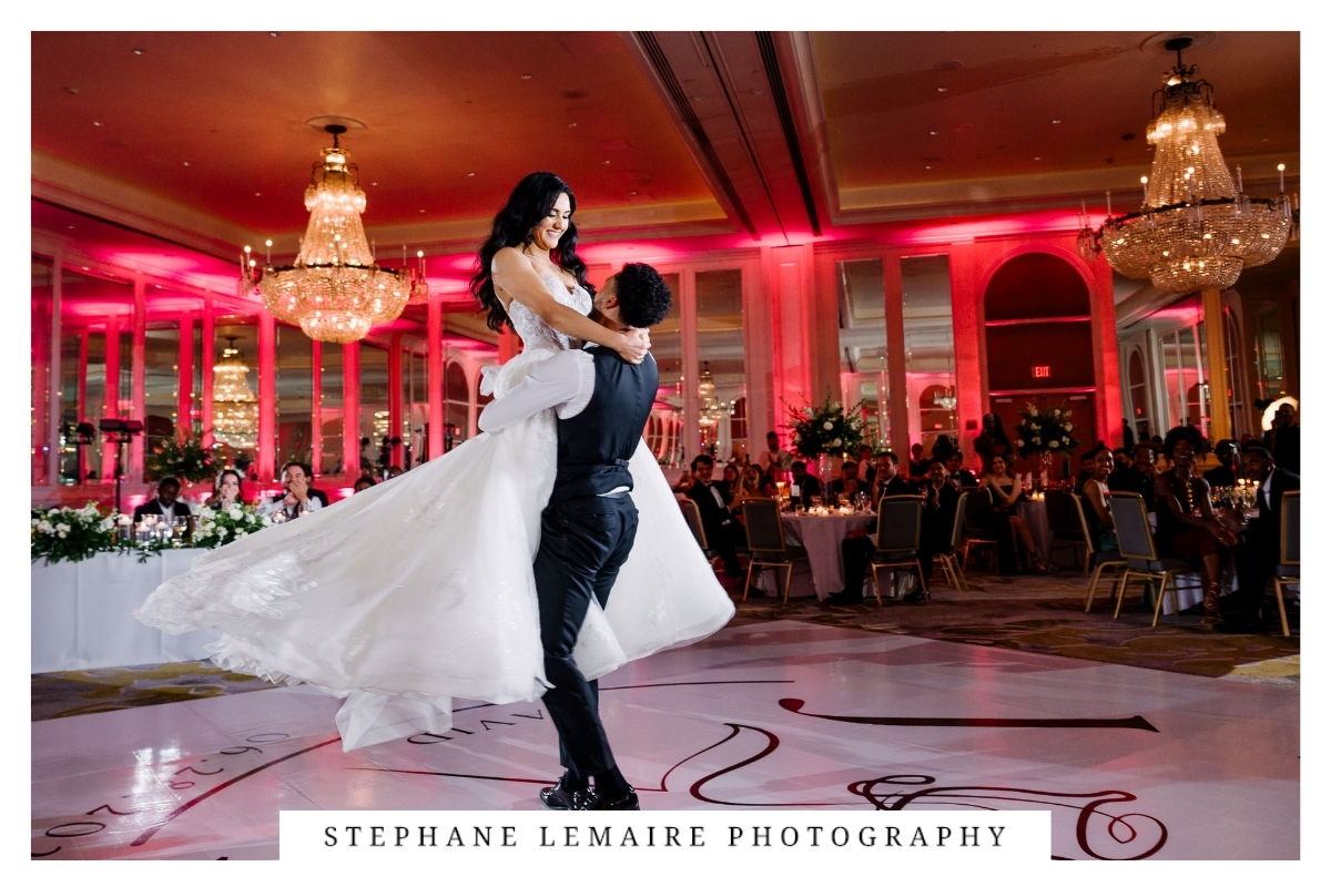 Groom lifting bride during the performance of their first dance surrounded by guests at Hotel Paso del Norte.