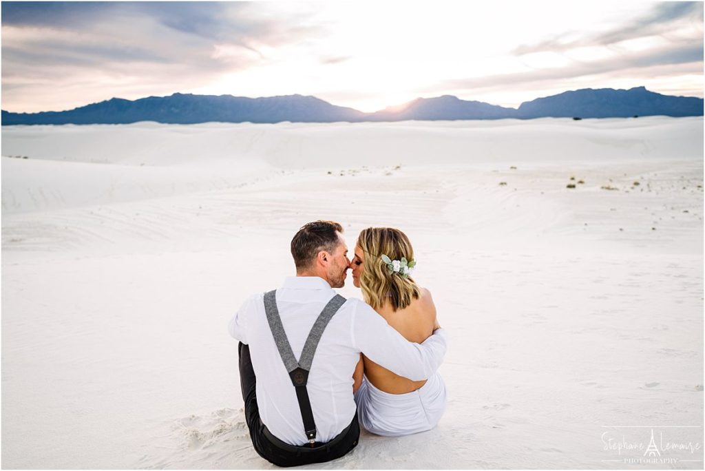 Bride and groom sitting down on sand at sunset at White Sand National monument New Mexico
